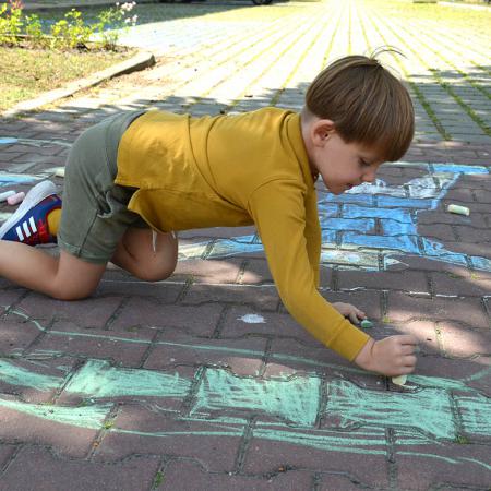 Chłopiec maluje kredą po chodniku