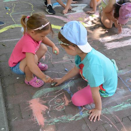 Dzieci malują kolorowe figury kredą