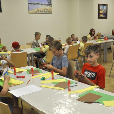 Na pierwszym chłopcy przy stole wycinają z papieru kolorowego różne kształty