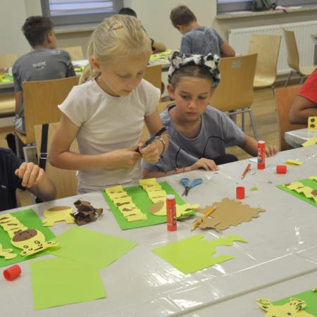 Dzieci przy stole z różnymi materiałami plastycznymi tworzy swoje prace
