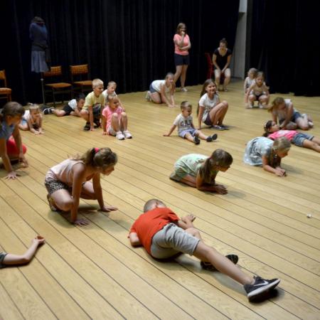 Dzieci w różnych pozach podczas teatralnych zajęć wakacyjnych