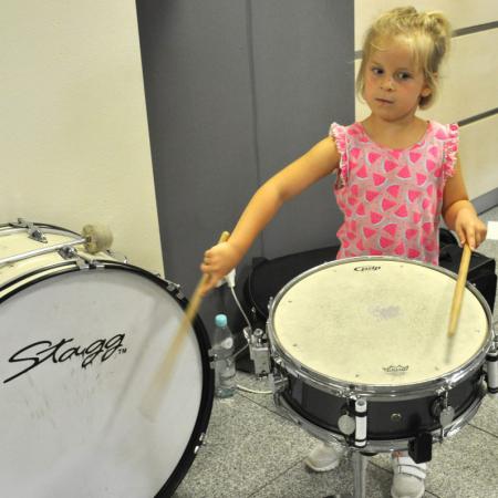 Mała dziewczynka gra na bębnie i perkusji