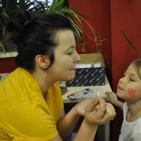 Malowanie ust dziewczynce. Dziecko zaciska usta jak instruktor