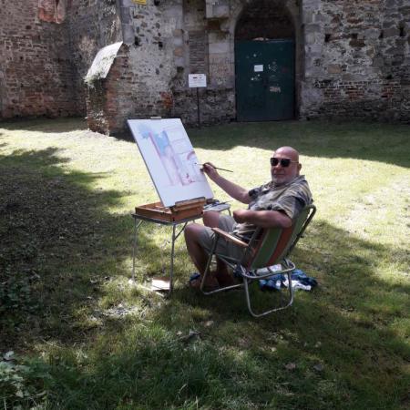 Mężczyzna siedzi koło zamku w Drzewicy i maluje obraz 