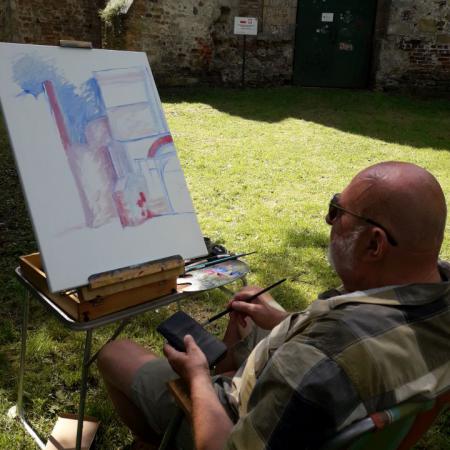 Mężczyzna siedzi i maluje bramę zamku w Drzewicy