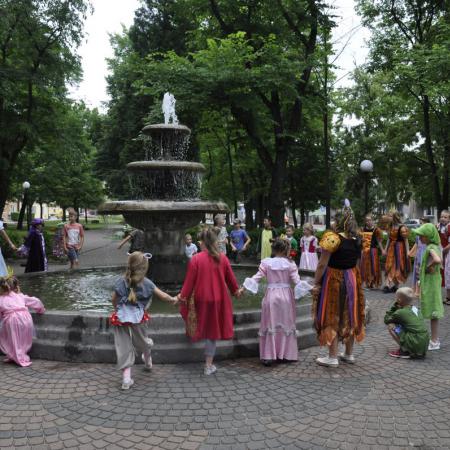 Przebrane dzieci stoją dookoła fontanny