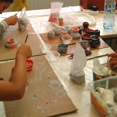 Dzieci malują szkliwem naczynia z gliny.