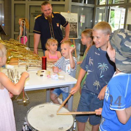 Grupa dzieci stoi przy stole z instrumentami dętymi