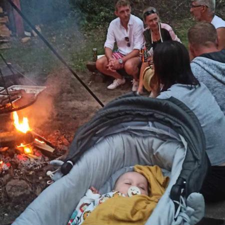 Na pierwszym planie chłopiec śpi w wózku, za nim widać kilka osób siedzących przy ognisku