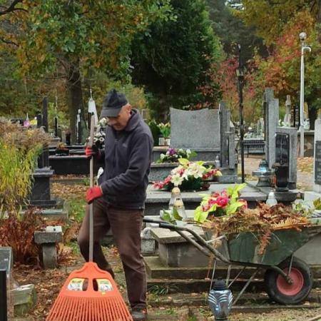 Mężczyzna sprząta zabytkowe groby na cmentarzu w Drzewicy