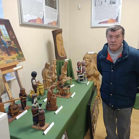 Mężczyzna stoi przy wystawie figurek z drewna 