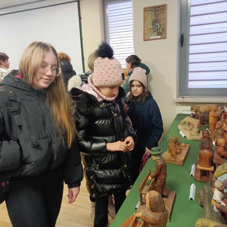 Młodzież ze szkoły ogląda figurki drewniane 