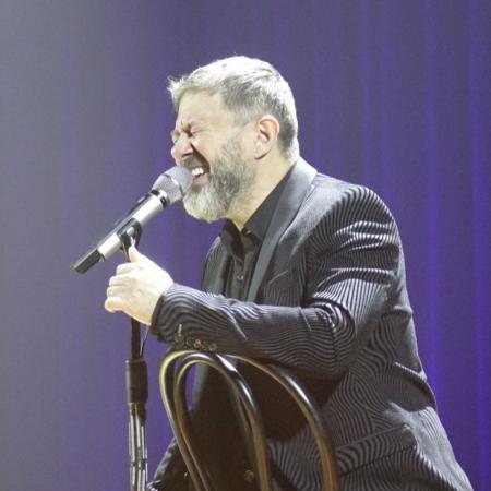 Andrzej Piaseczny śpiewa na krześle przez mikrofon 