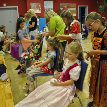 Dzieci i dorośli w przebraniach robią sobie fryzury przed lustrem