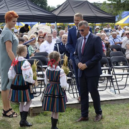 Dziewczynki w ludowych strojach wręczają Burmistrzowi gminy Drzewica oraz Radnemu Gminy bukiety z kwiatów i zbóż z tegorocznych plonów