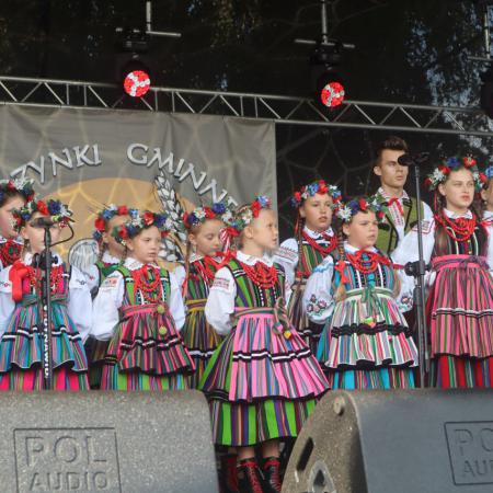 Grupa osób w ludowych strojach występuje na scenie 