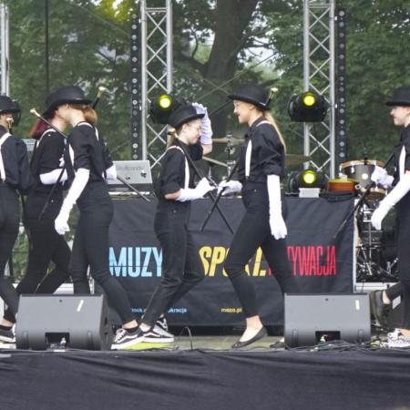 Uczestniczki zajęć tanecznych podczas występu ubrane w czarne stroje i meloniki