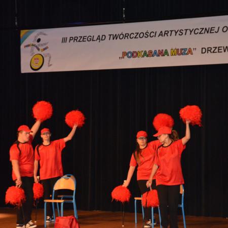 Cztery osoby w czerwonych strojach tanczą na scenie