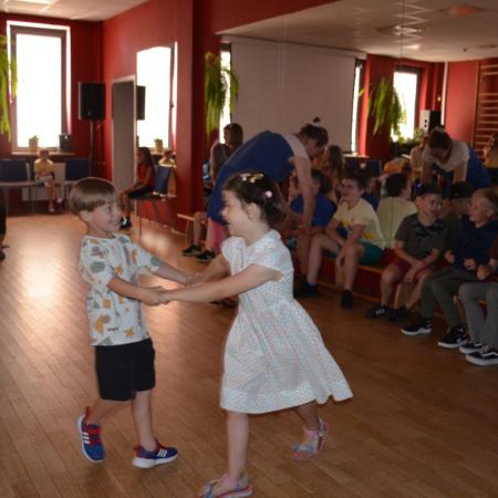 Dziewczynka i chłopiec tańczą trzymając się za ręce