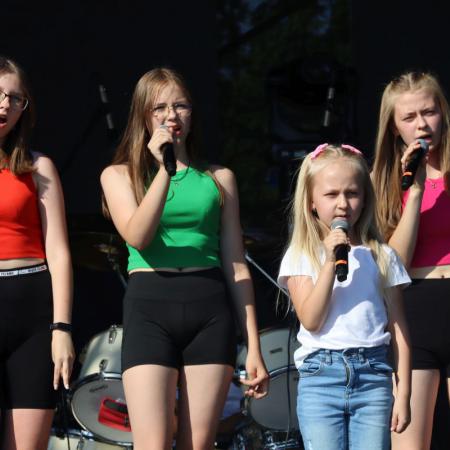 Cztery dziewczyny śpiewają na scenie przy mikrofonach