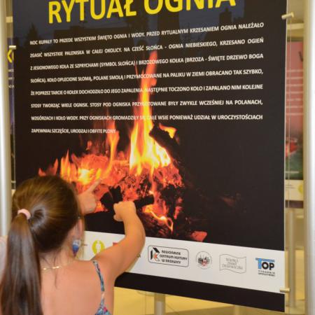 Dziewczynka ogląda tablice wystawienniczą "Rytuał ognia"