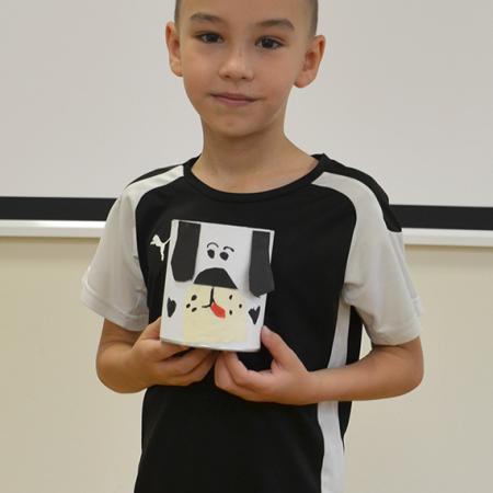 Chłopiec trzyma przybornik w kształcie pieska  wykonany na zajęciach