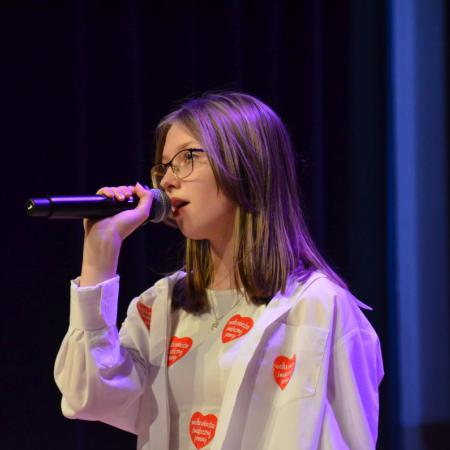 Dziewczyna śpiewa przy mikrofonie na scenie podczas WOŚP 