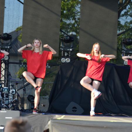 Dziewczyny tańczą na scenie unosząc nogę i ręce do góry 