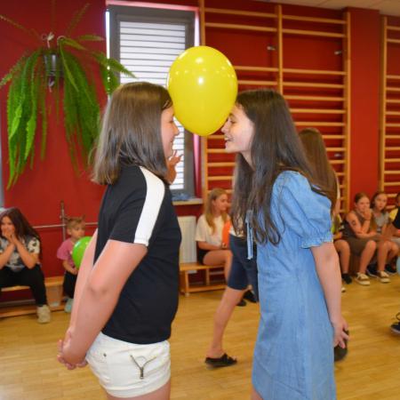 Dwie dziewczynki trzymają balon między głowami