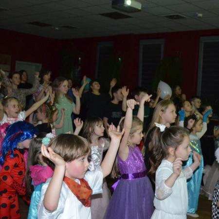Dzieci w przebraniach tańczą unosząc ręce do góry