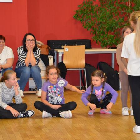 Dzieci siedzą na podłodze podczas udziału w zabawie.