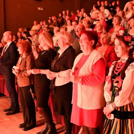 Publiczność stoi w skupieniu, wspólnie śpiewając.