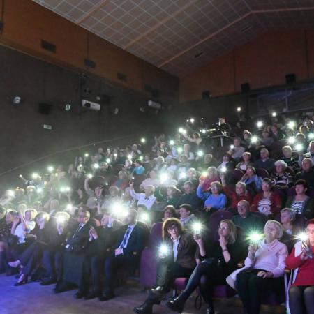 Widownia trzyma zapalone latarki w telefonach, tworząc efekt morza świateł podczas koncertu