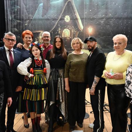 Grupa ludzi pozuje do wspólnego zdjęcia pamiątkowego na tle scenografii wydarzenia