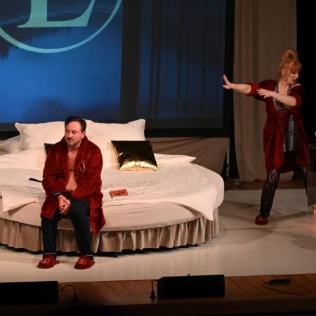 Mężczyzna siedzący na łóżku, w tle tańcząca kobieta.