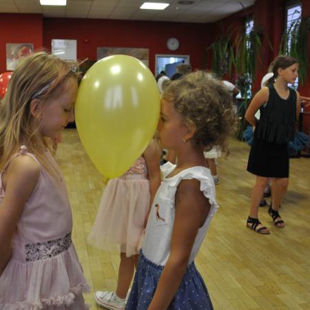 Dwie dziewczynki na pierwszym planie tańczą z balonem