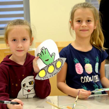 Dwie dziewczynki pokazują wykonane prace plastyczne