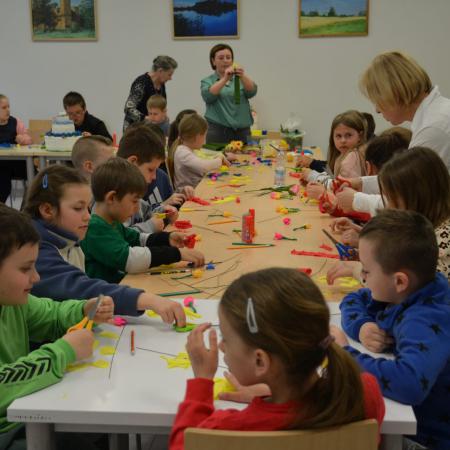 Dzieci na warsztatach wykonują kwiaty z bibuły.
