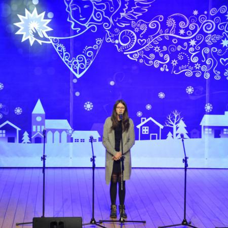 Dziewczyna wieku szkolnym spiewająca na scenie , w tle Mikołaj