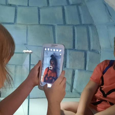 Dziewczynka robi zdjęcie telefonem drugiej dziewczynce w igloo