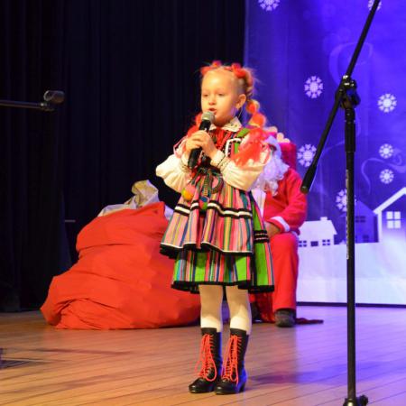 Dziewczynka w stroju ludowym śpiewajaca na scenie.