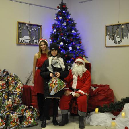 Dziewczynka  z prezentem od Mikołaja stoi obok Śnieżynki i św Mikołaja