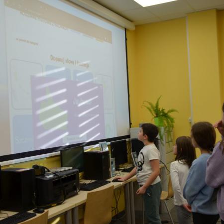 Grupa dzieci stoi przy ekranie projektora