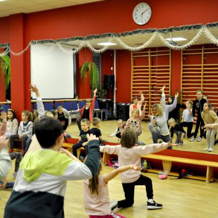 Grupa dzieci z instruktorem zajęć tańczą przed lustrem