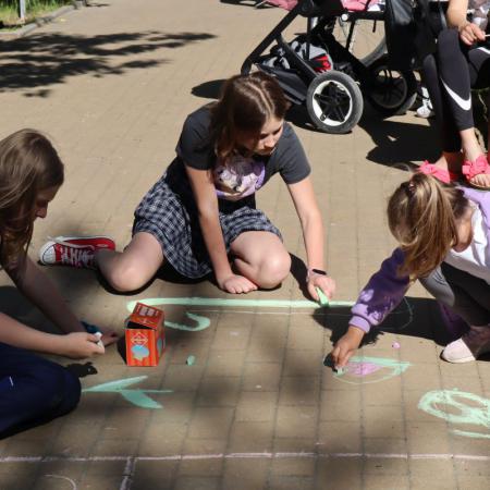 Dziewczynki malują kredą po chodniku 