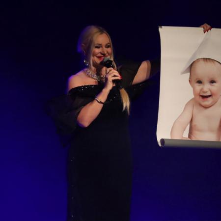 Kobieta stoi ze zdjęciem dziecka na scenie