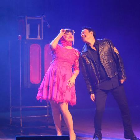 Kobieta w czerwonej sukience i Maciej Po występują na scenie
