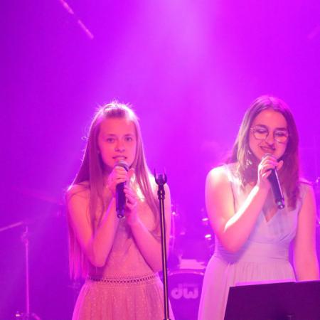 Dziewczyny śpiewają przy mikrofonach na scenie podczas koncertu