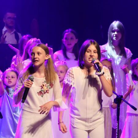 Dziewczyny śpiewają przy mikrofonie na scenie podczas Koncertu Uwielbienia w RCK