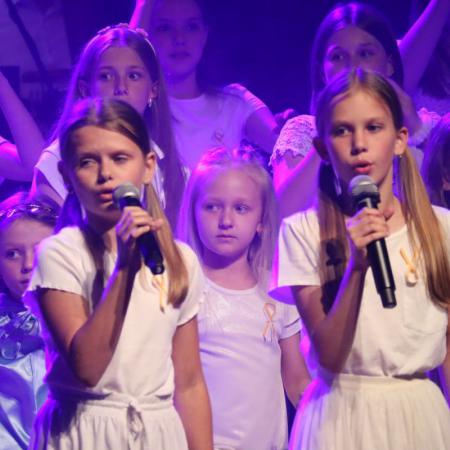 Dziewczyny śpiewają przy mikrofonie na scenie podczas Koncertu Uwielbienia w RCK